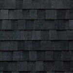 Close-up view of dark gray asphalt roof shingles arranged in a repetitive, staggered pattern, creating a textured, overlapping surface.