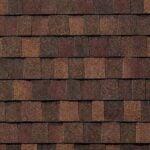 A close-up view of overlapping brown and reddish asphalt roof shingles arranged in a staggered pattern, showing their rough, granular texture.