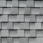 Gray asphalt roof shingles arranged in a regular, overlapping pattern, creating a textured surface.