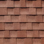 Close-up view of overlapping reddish-brown asphalt roof shingles arranged in a staggered pattern.