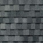 Gray asphalt roof shingles arranged in an overlapping, horizontal pattern, creating a textured surface typical of residential roofing.