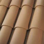 Close-up view of overlapping, curved, tan clay roof tiles arranged in a repeating pattern, forming a traditional roofing surface.