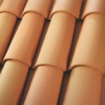 Close-up of overlapping terracotta roof tiles arranged in neat, horizontal rows, showing their curved shape and smooth, reddish-brown surfaces.
