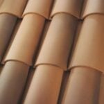 Close-up view of overlapping curved terracotta roof tiles arranged in neat rows, with varying shades of brown and tan.