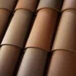 Close-up view of overlapping brown ceramic roof tiles arranged in neat, parallel rows, showing their smooth texture and subtle color variations.