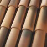 Close-up of overlapping terracotta roof tiles arranged in neat rows, showing shades of brown and tan with some darkened areas, creating a textured and patterned surface.