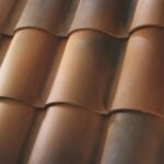 Close-up of overlapping reddish-brown clay roof tiles, showing their curved shape and smooth texture, arranged in neat, horizontal rows.
