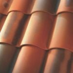 Close-up view of red-brown ceramic roof tiles, arranged in overlapping rows with a curved, wavy design.