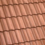 Close-up view of brown terracotta roof tiles arranged in neat, overlapping rows, creating a wavy, textured pattern.
