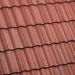 Close-up view of red, wavy roof tiles arranged in neat horizontal rows, creating a textured and uniform pattern typically seen on residential rooftops.