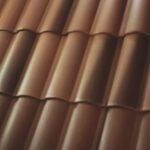 Close-up of brown, overlapping, wavy roof tiles arranged in parallel rows, creating a repeating pattern. The surface appears smooth with subtle highlights and shadows.