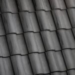 Close-up view of dark gray ceramic roof tiles arranged in overlapping rows, creating a textured and uniform pattern.