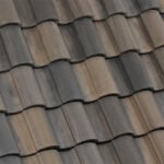 Close-up view of overlapping, curved, brown and gray concrete roof tiles arranged in neat, horizontal rows, illustrating a textured pattern.
