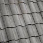 Close-up of gray ceramic roof tiles arranged in a repeating, overlapping pattern, giving the surface a textured and uniform appearance.