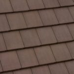 A close-up view of a brown tiled roof with overlapping rectangular tiles arranged in neat, horizontal rows.