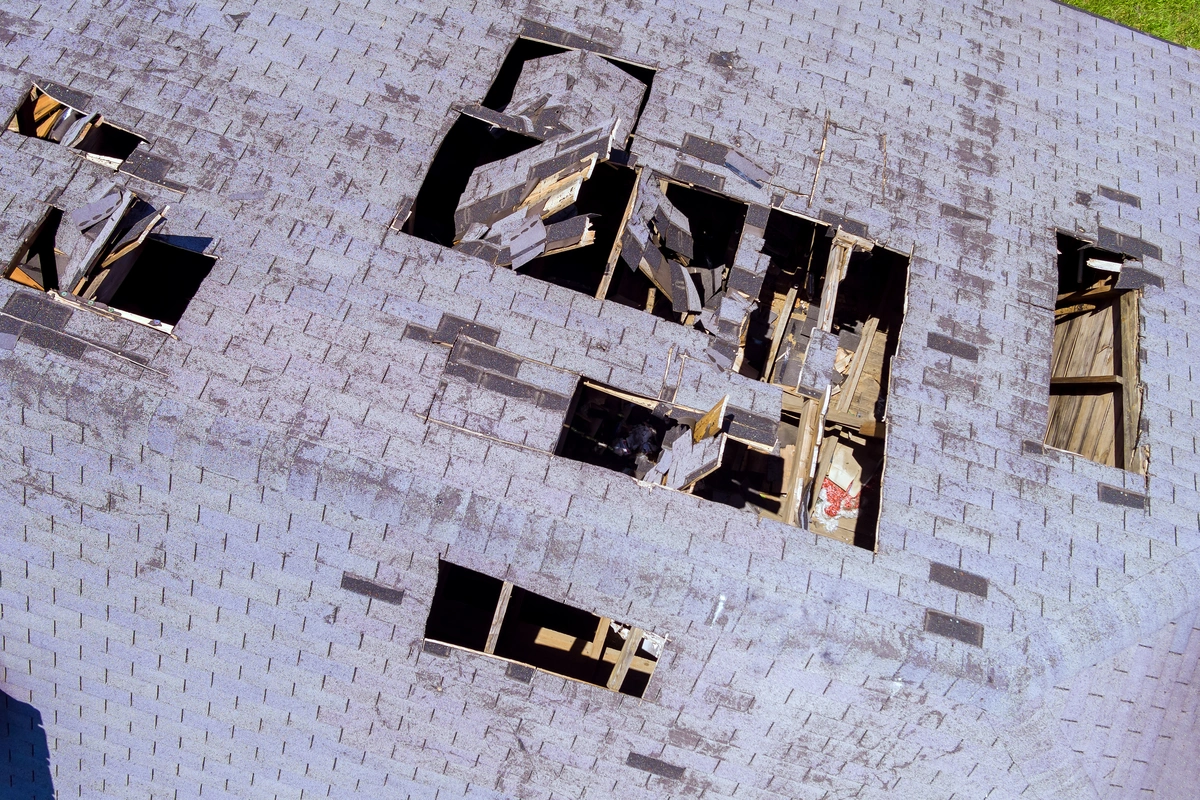 large house roof with blown off shingles before repair