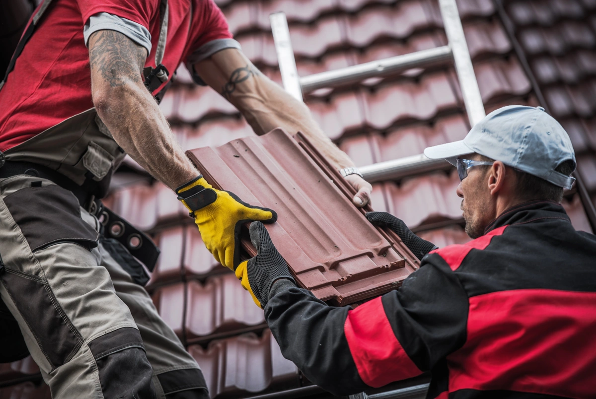 professional roofers using red roof tiles for the house
