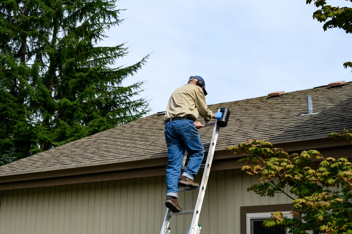 homeowner on ladder to clean roof