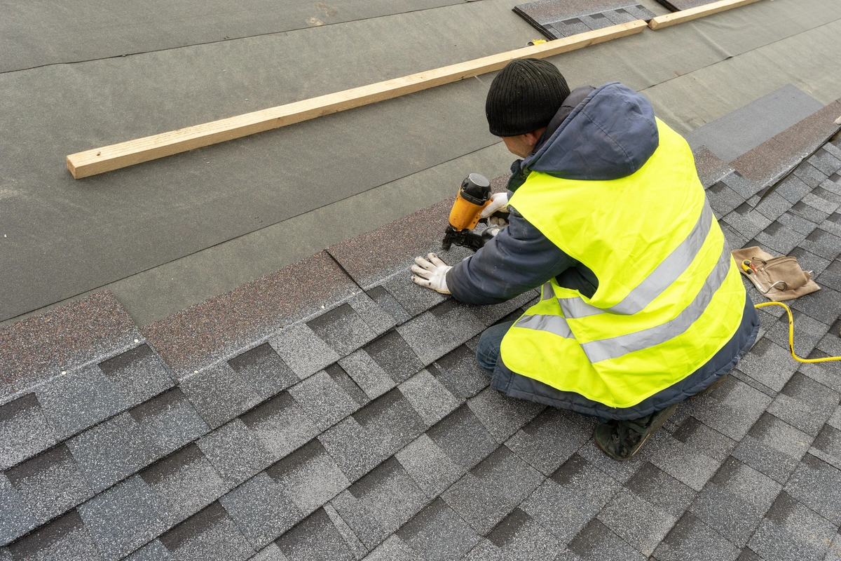 a roofer installs asphalt shingles