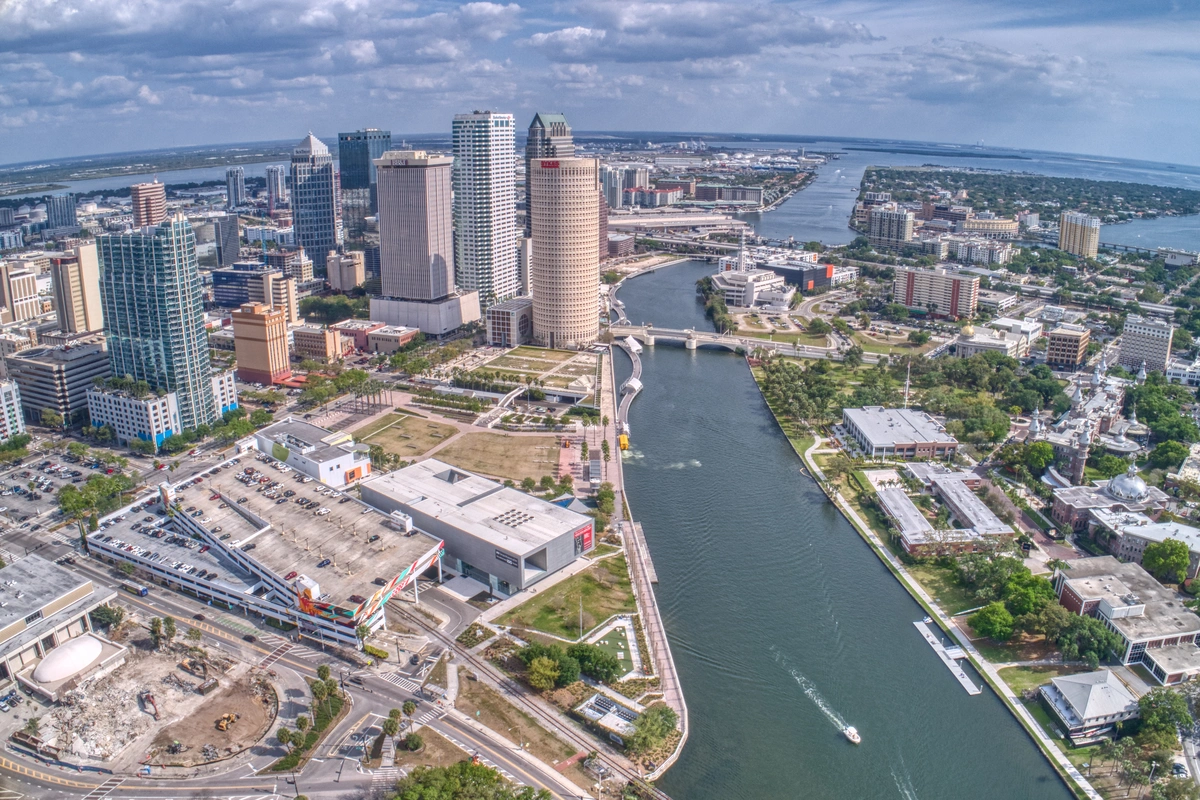 Aerial view of downtown Tampa, Florida, showing high-rise buildings, the Hillsborough River, bridges, and nearby neighborhoods—home to some of the best restaurants in Tampa—under a partly cloudy sky.