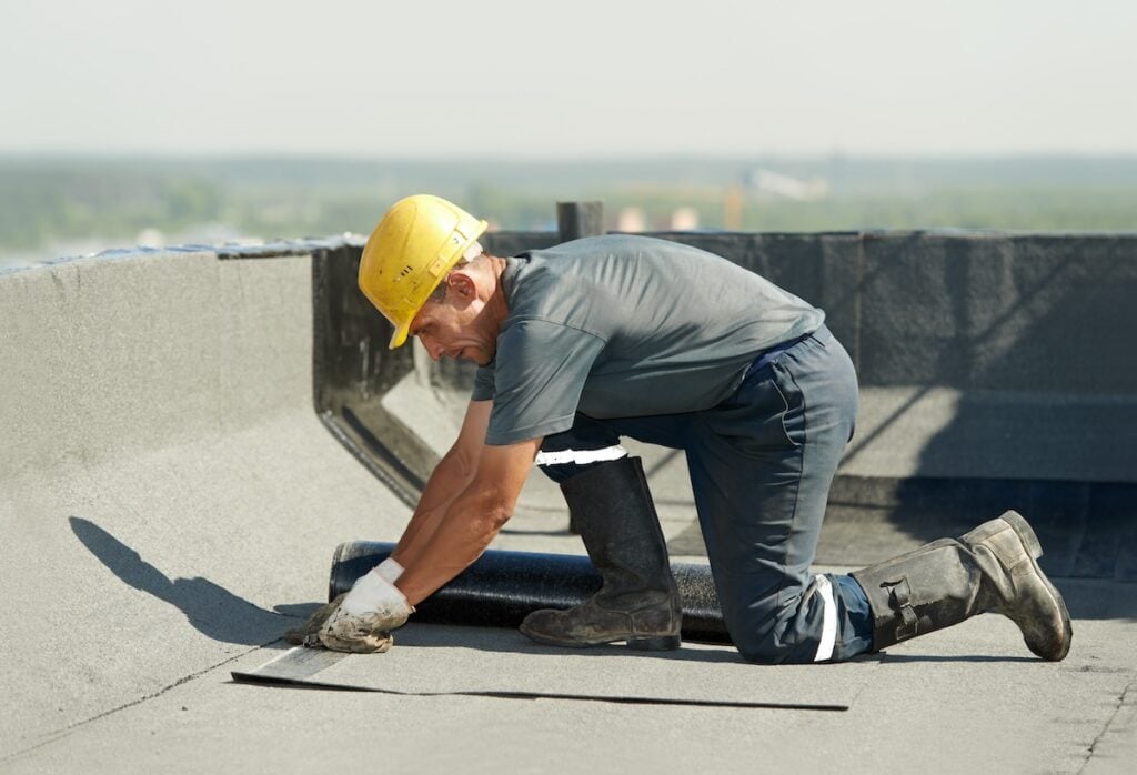 worker repairing flat roof leak