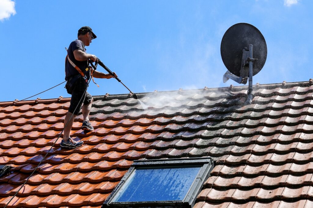 man power washing tile roof