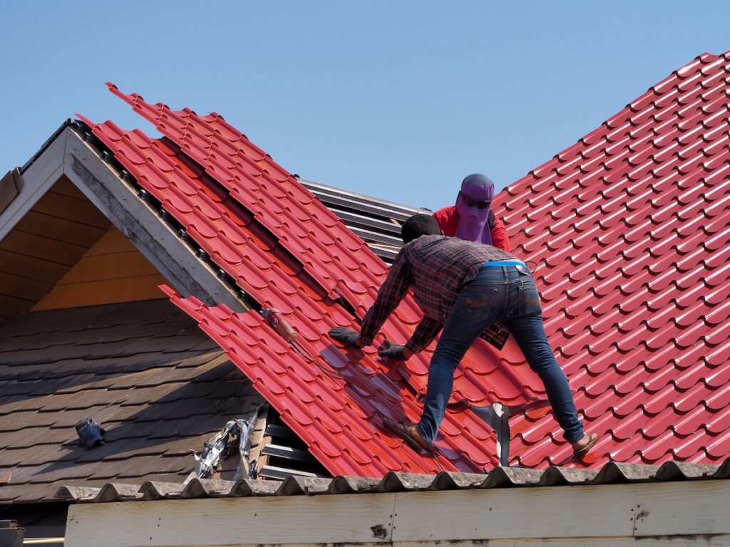 Man removing rust from white metal roof with grinding tool. Man holding grinder. Roof maintenance. Rust removal.