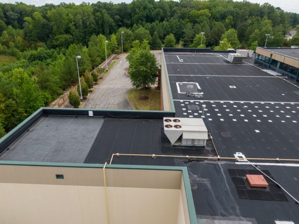 epdm roof sealant commercial building surrounded by pine trees drone inspection