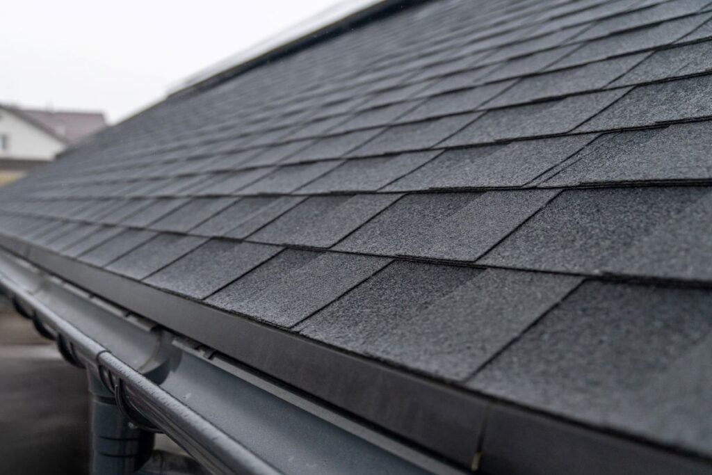 shingle vs metal roofing Wesley mchapel close up grey shingles roof and gutter water system